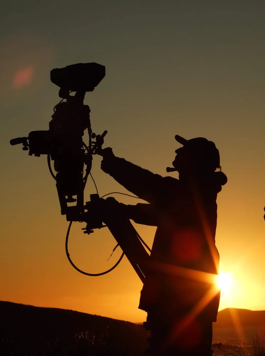 silhouette of a camera operator using a jib at sunset